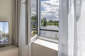 Ein Fenster mit Blick auf einen See, eine Anlegestelle mit Booten und ein Wohngebiet.