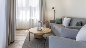Una sala de estar moderna con un sofá gris, una mesa redonda de madera y una lámpara de pie.