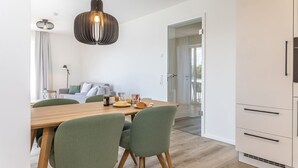 Una cocina moderna con una mesa de comedor de madera, sillas verdes y una lámpara colgante.