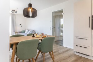 Eine moderne Küche mit einem Holzes Esstisch, grünen Stühlen und einer Pendelleuchte.