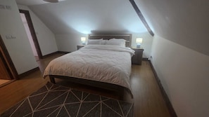 A single bed in a room with a sloped ceiling, a bedside table with a lamp, and a patterned rug. - Thatch cottage historical attractions, medical centre fantastic landscapes (Clonmel)