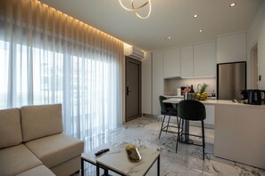Ein modernes Wohnzimmer mit einer Couch, einem Couchtisch und einer Küchenzeile mit Esstisch und Stühlen.