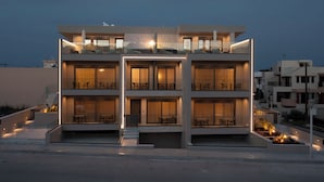 Un immeuble à plusieurs étages doté de balcons, de grandes fenêtres et d’espaces extérieurs aménagés pour s’asseoir.