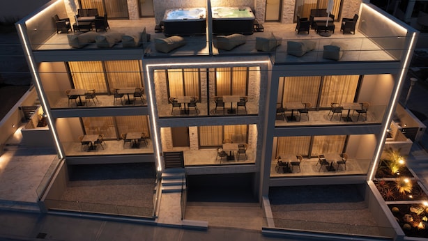 Un hôtel à plusieurs étages doté d’une façade en verre, d’espaces extérieurs aménagés et d’un jacuzzi situé au dernier étage.
