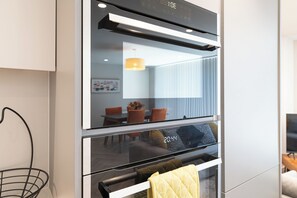 Eine moderne Küche mit eingebautem Ofen und Mikrowelle, ein Essbereich mit Tisch und Stühlen sowie eine hängende Leuchte.