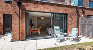 A brick house with a sliding glass door leading to a dining area with a table and chairs. - Wimbledon Tennis - 3BR/2BA clean modern apartment with 1GB Wi-Fi and local host (London)