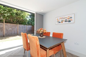 A dining area with a table, chairs, and a vase of flowers. - Wimbledon Tennis - 3BR/2BA clean modern apartment with 1GB Wi-Fi and local host (London)