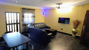 Ein Wohnzimmer mit einer Couch, einem Tisch und einem an der Wand befestigten Fernseher.