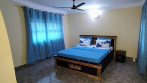 Ein Schlafzimmer mit einem Bett, Vorhängen, einem Deckenventilator und einem kleinen Nachttisch.