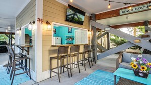 Uma casa de praia com área de bar, espaço para sentar ao ar livre e uma escadaria.
