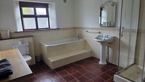 A bathroom with a bathtub, toilet, sink, and a shower area.