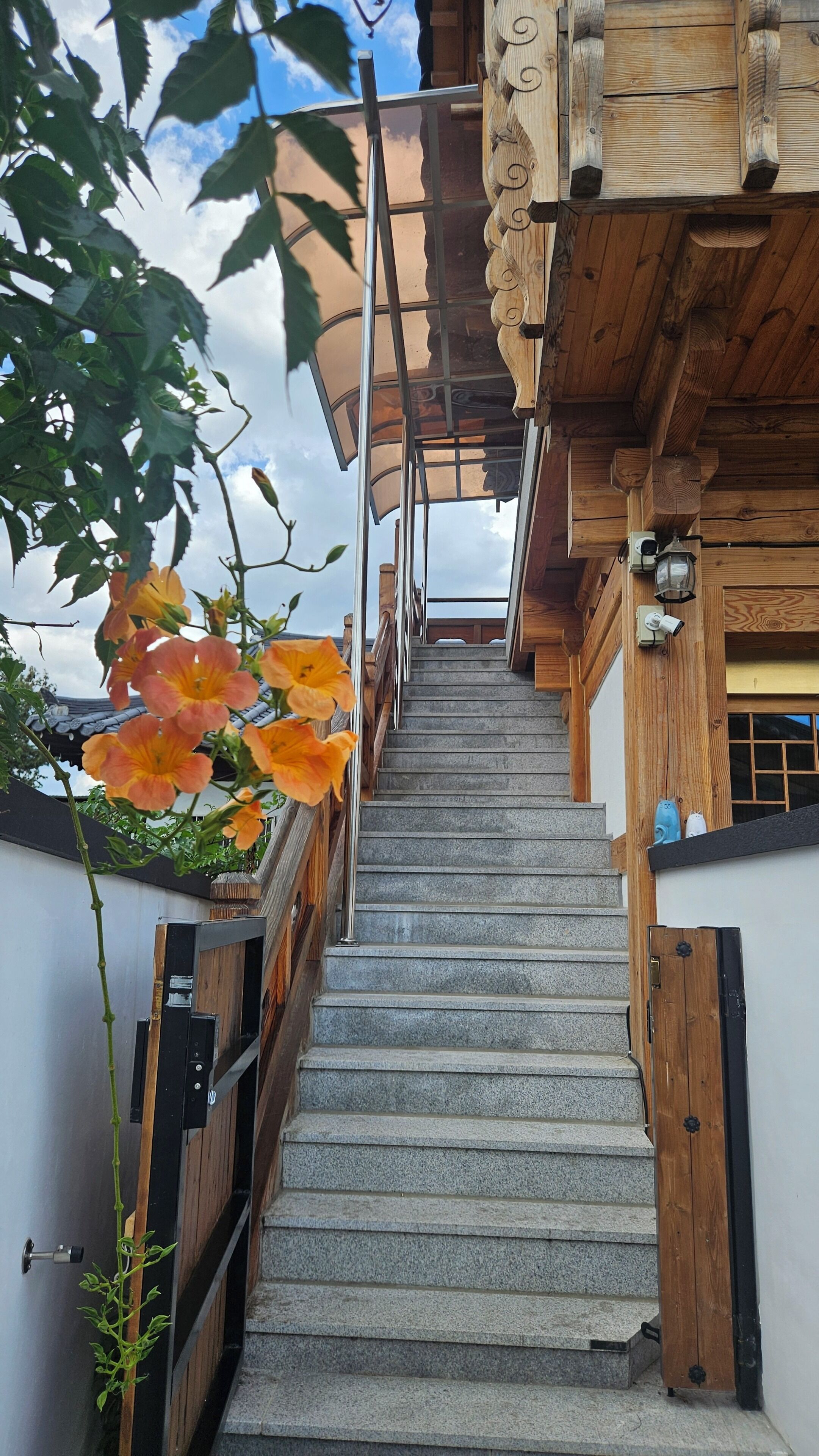 A staircase leading to a wooden structure with a traditional design, a metal railing, and a view of the sky.