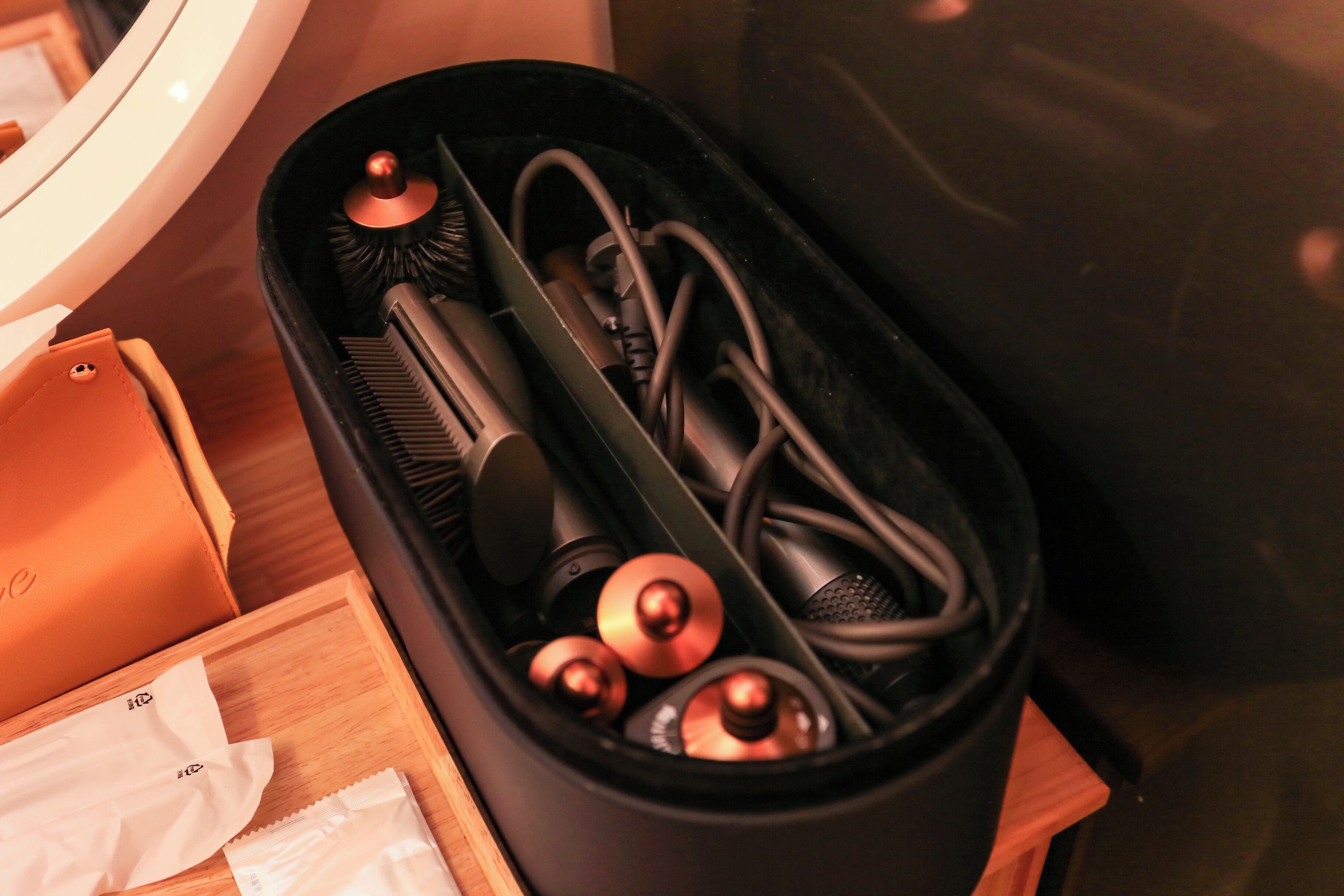 A black case with a brush, a cylindrical object, and a cord inside.