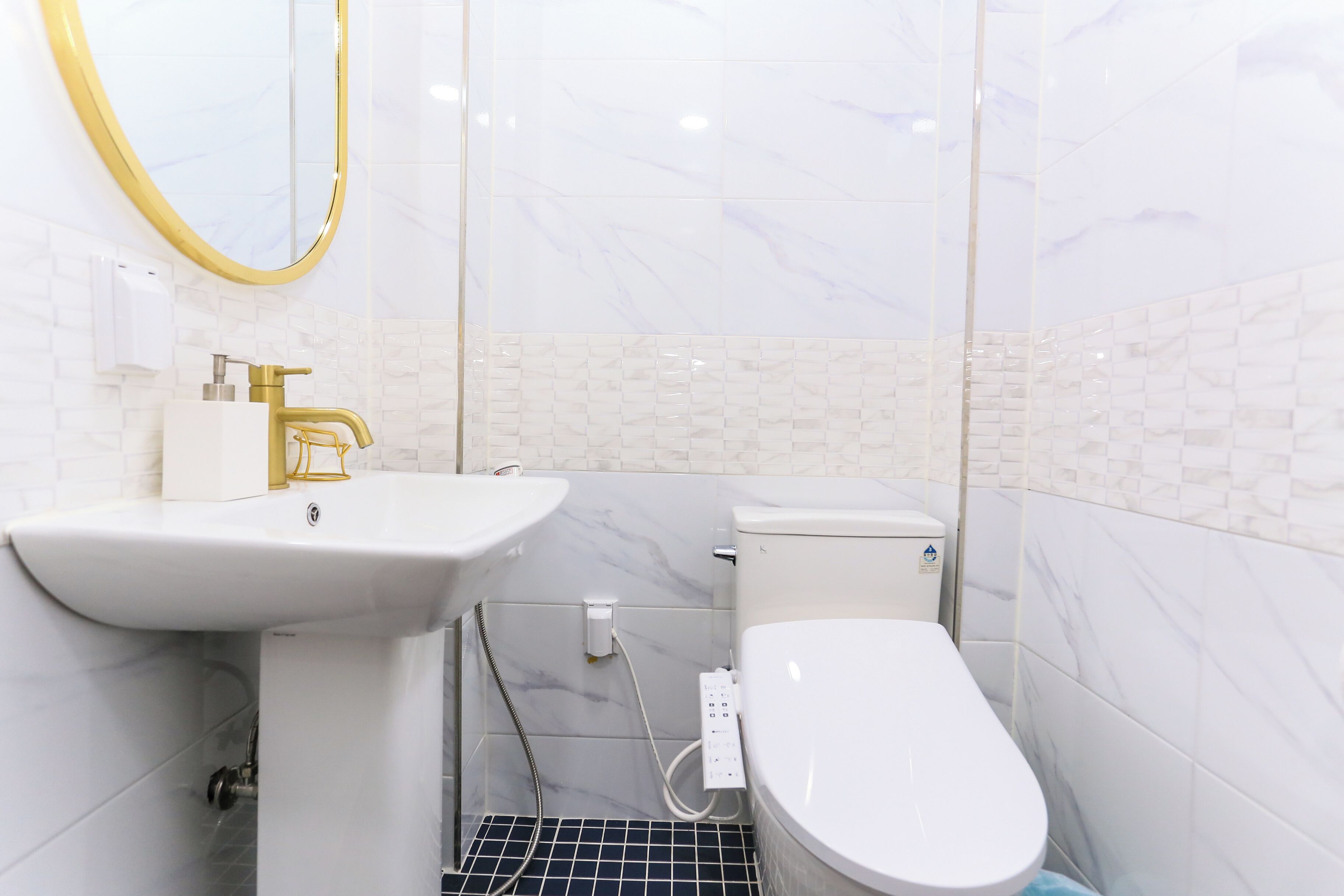 Un baño con lavamanos blanco, grifo dorado y un inodoro.