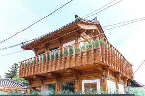 Un edificio tradicional de madera con un balcón, barandillas de madera y techo de tejas.