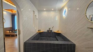 A modern bathroom with a freestanding bathtub, a large mirror, and a wooden bench in the adjacent room. - Modam Stay Gyeongju (Gyeongju-si)