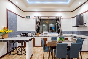 Een moderne keuken met een centraal eiland, barstoelen, een eettafel met stoelen en een televisie op de achtergrond.