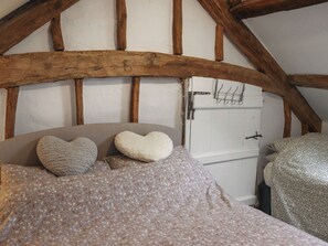 A bedroom with a wooden ceiling, a bed with floral bedding, and a white door with a metal handle. - 3 bedroom accommodation in Dolgellau (Dolgellau)