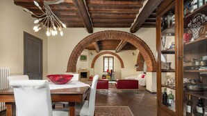 Un comedor con una mesa de madera, sillas, un cuenco rojo y una alfombra estampada.