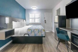 Ein modernes Schlafzimmer mit Bett, Nachttisch, Schreibtisch, Stuhl und einem eingebauten Fernseher.