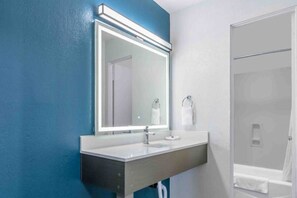 Une salle de bain avec un grand miroir, un lavabo et une douche.