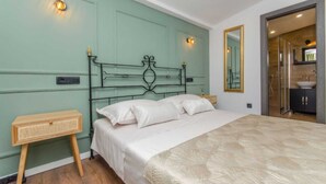 A bedroom with a bed, bedside tables, a mirror, and a bathroom visible through an open door. - Villa sa bazenom i jacuzzijem u Dalmatinskoj zagori na 20 min od Splita (Biorine)