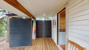 Un'area esterna riparata con un pavimento in legno, una porta scorrevole e vista su una cucina.