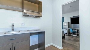 Una cocina moderna con horno empotrado, un lavamanos y una encimera. Hay una zona de comedor separada con una mesa y sillas.