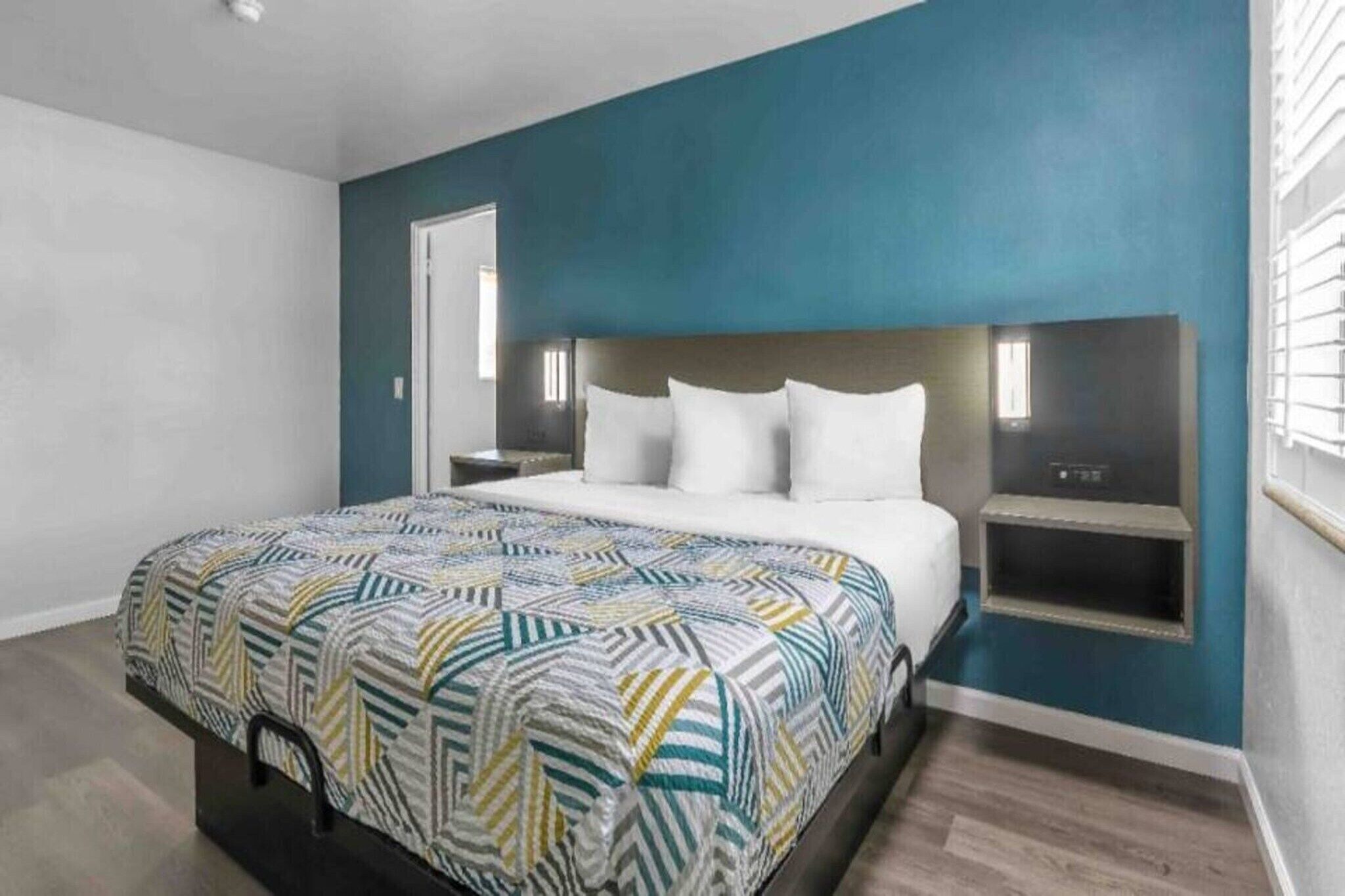 A bedroom with a bed, bedside tables, and a window.