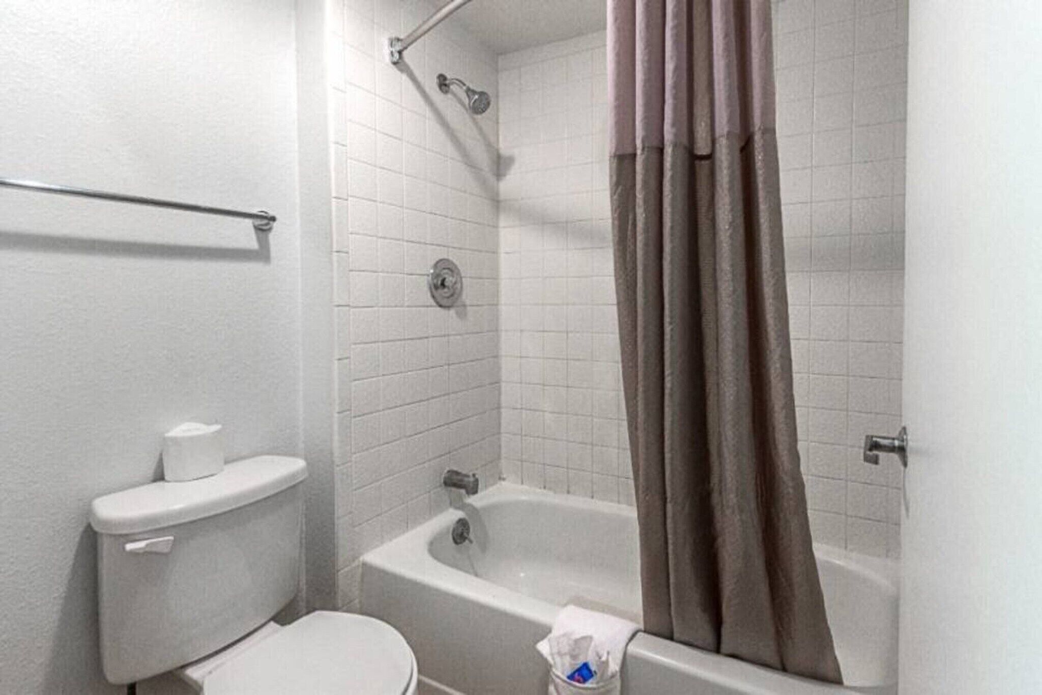 Een badkamer met toilet, bad en douchegordijn.
