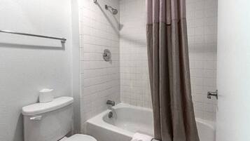 Een badkamer met toilet, bad en douchegordijn.
