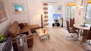 Ein modernes Wohnzimmer mit einer Couch, Couchtisch, Fernseher und Essbereich.