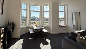 Ein geräumiges Wohnzimmer mit großem Fenster, einem Esstisch und einer Couch.