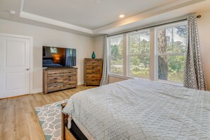 A bedroom with a large bed, a dresser, a television, and a window with a view of trees. - 5 Mi to Bethany Beach! Group Escape w/ Pool Access (Ocean View)