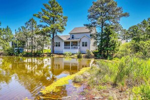 Uma casa com varanda, cercada por árvores e um lago.