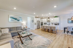 Un salon moderne avec un canapé, une table basse et un tapis. Il y a également un coin cuisine équipé de placards, d’un réfrigérateur et d’une table à manger avec des chaises.