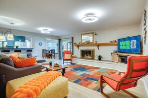 A living room with a sofa, ottoman, and a television displaying the FIFA World Cup logo. - Hot Tub & Game Room! Home 15 Mi to AT&T Stadium (Fort Worth)