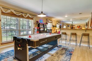 A pool table with a neon sign, bar stools, and a view of trees through large windows. - Hot Tub & Game Room! Home 15 Mi to AT&T Stadium (Fort Worth)