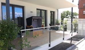 A covered outdoor area with a grill, seating, and potted plants. - Villa Amelie, App. Baltic Sea - with sea view (Sassnitz)