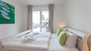 Habitación de hotel con dos camas, un cuadro en la pared y vistas al exterior.