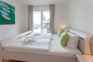 A hotel room with two beds, a painting on the wall, and a view of the outside. - Villa Amelie, App. Baltic Sea - with sea view (Sassnitz)
