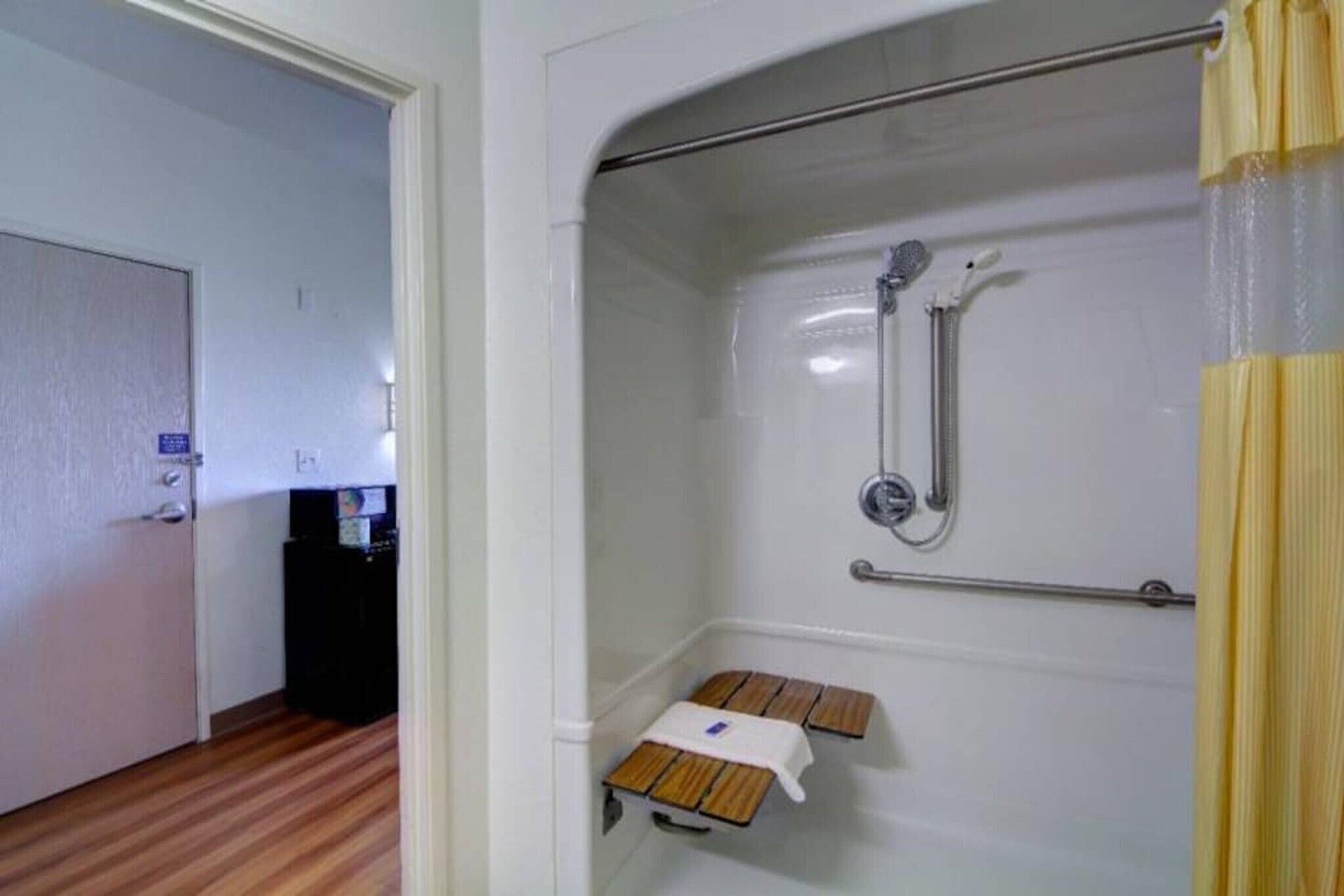 Eine Dusche mit Handbrause, einem Handtuchhalter und einer Holzbank.