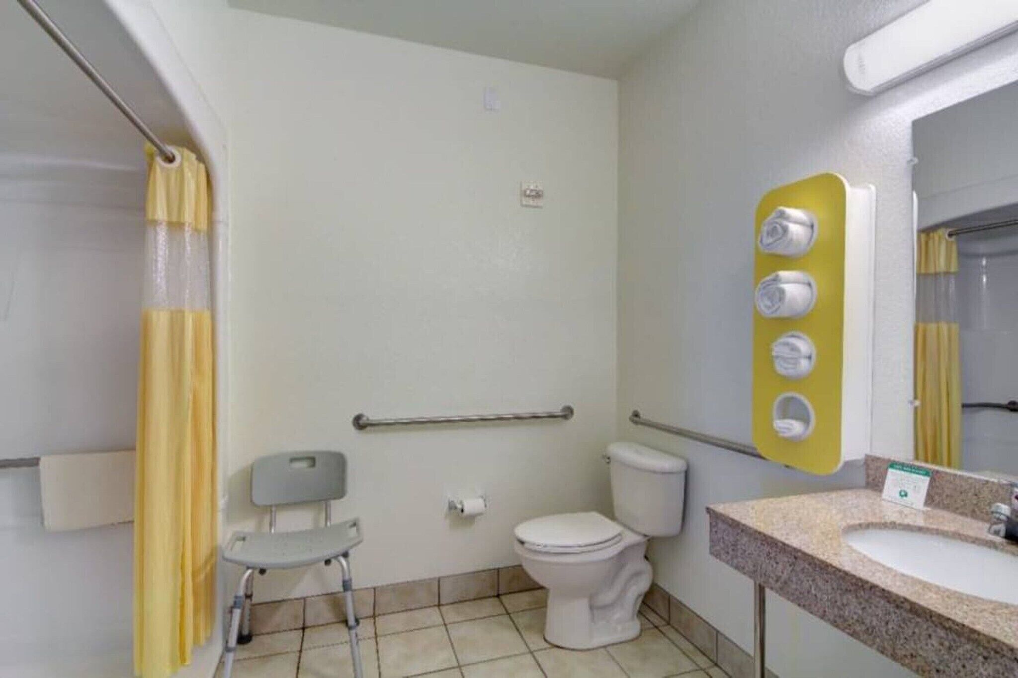 A bathroom with a toilet, a sink, a mirror, a shower curtain, and a grab bar.