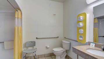 A bathroom with a toilet, a sink, a mirror, a shower curtain, and a grab bar.