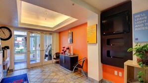 A hotel lobby with a reception desk, a clock, a plant, and a sign about light and rates. - 2 Queen Beds|Non-Smoking (El Reno)
