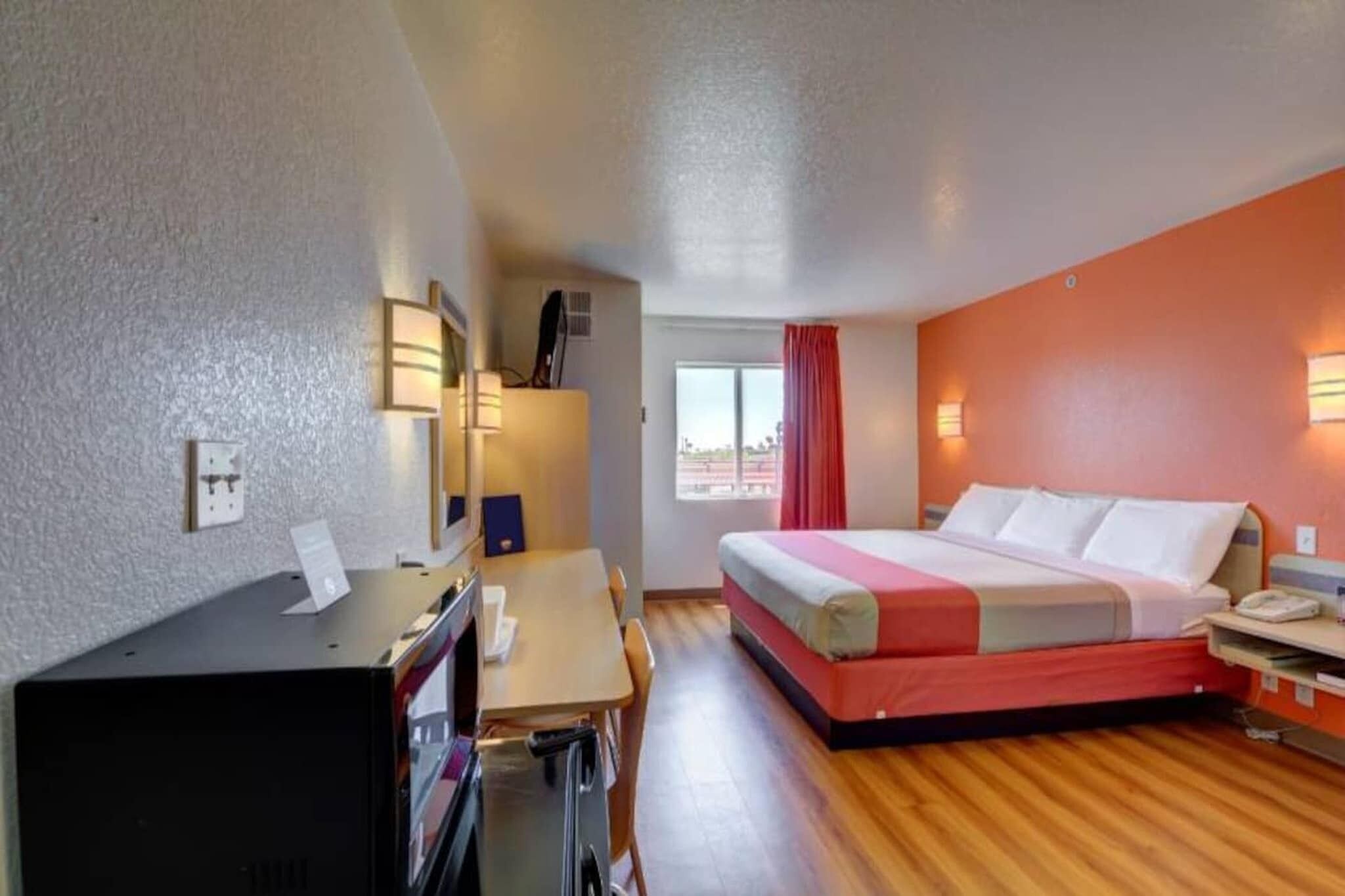 A hotel room with a bed, desk, and a window with curtains.