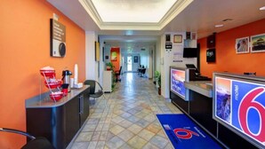 Un'area reception di un hotel con pavimento piastrellato, una scrivania della reception e un cartello con la scritta 'motel 6'.