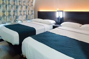 A hotel room with two beds, a patterned curtain, a wall-mounted lamp, and a dark headboard. - 2 Full Beds | Micfridge, Smoking (Fresno CA)