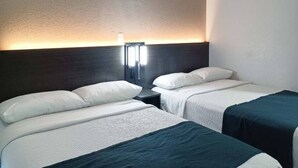 Ein Hotelzimmer mit zwei Betten, einem Nachttisch und einer Wandlampe.