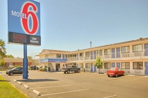 A motel with a large sign, a parking lot, and a building with multiple rooms. - ADA Full Bed|RI Shr|Smk (Fresno CA)